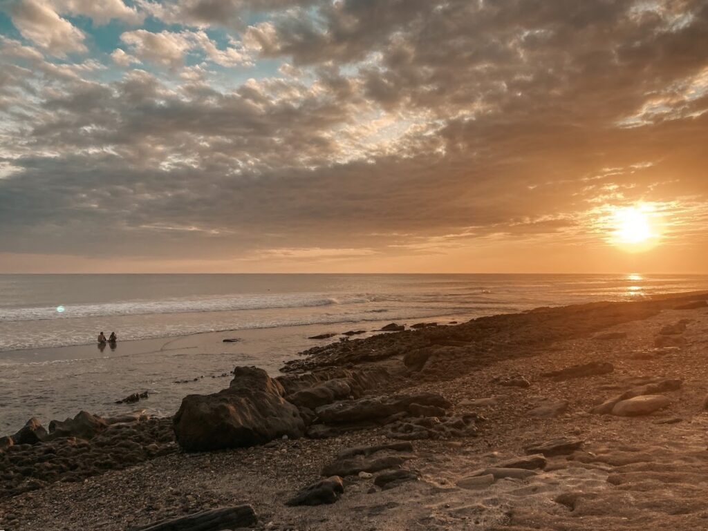 a beach with rocks and a couple of people on the beach